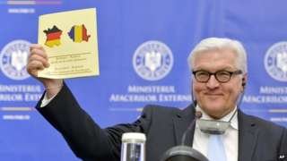 German Foreign Minister Frank-Walter Steinmeier holds up a document celebrating 135-years of German - Romanian diplomatic relations